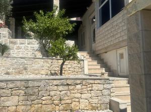 a stone wall next to a building with a tree at Holiday Home Aurora in Splitska +24 photos