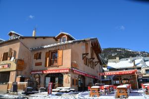 a building with tables and chairs in the snow at H&ocirc;tel Alpis Cottia in Montgen&egrave;vre