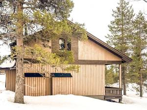a wooden building with a tree in the snow at Holiday Apartment Hirvas 1 in Saariselka