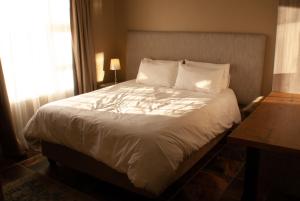 a bedroom with a bed with white sheets and a window at Casa de la Presa 1 in Polokwane +26 photos