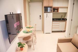 a small kitchen with a table and a refrigerator at Flats no centro de Porto de Galinhas próximo à praia opções com e sem piscina privativa in Porto De Galinhas