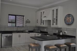 a kitchen with white cabinets and a black counter top at Mountain Villa 238 in Clarens