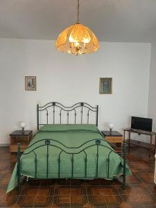 a bedroom with a green bed and a chandelier at B&B Villa Machi in Paola