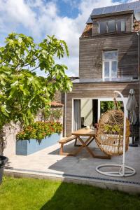 a patio with a wooden table and a rattan chair at 3 Kings in Bruges