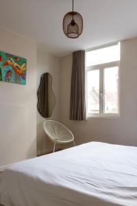 a bedroom with a bed and a chair and a window at 3 Kings in Bruges