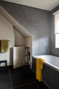 a bathroom with a tub and a washing machine at 3 Kings in Bruges