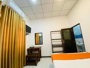 a room with yellow curtains and a bed and a table at Thirasara Family Garden in Medawachchiya