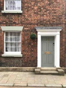 a brick building with a green door and two windows at Stunning City centre Georgian townhouse - parking in Chester