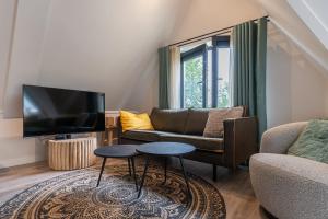 ein Wohnzimmer mit Sofa und Fernseher in der Unterkunft Hello Zeeland - Appartement Duno Lodge M in Oostkapelle