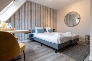 ein Schlafzimmer mit einem Bett, einem Tisch und einem Spiegel in der Unterkunft Hello Zeeland - Appartement Duno Lodge M in Oostkapelle