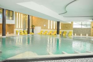 a large swimming pool with yellow chairs in a building at Thalazur Arcachon in Arcachon