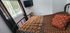 a bedroom with a bed with a blanket and a window at Maison au Pied du Mont Video in Barraute