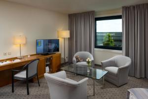 a hotel room with a desk and chairs and a table at Maritim Airport Hotel Hannover in Hannover