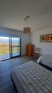 a bedroom with a bed and a sliding glass door at Mirada al Champaquí - Chalet de Montaña in Villa Yacanto