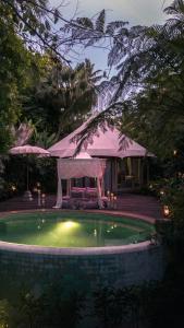 a small pool in a yard with an umbrella at Sandat Glamping Tents in Ubud