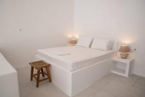a white bedroom with a white bed and a stool at Thavma Boathouse in Firopótamos
