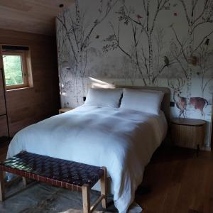 Un dormitorio con una gran cama blanca con un banco. en BANDIAT Le Domaine, en Fargeas