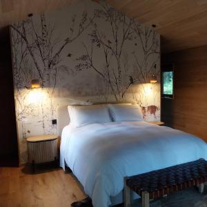 1 dormitorio con 1 cama blanca y un mural en la pared en BANDIAT Le Domaine, en Fargeas