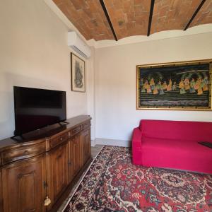 a living room with a red couch and a flat screen tv at La Rosa Rossa in San Casciano dei Bagni
