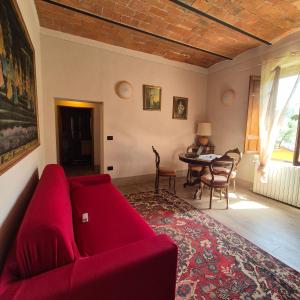 a living room with a red couch and a table at La Rosa Rossa in San Casciano dei Bagni