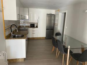 a kitchen with white cabinets and a table and chairs at Panxón Primera Linea Mar in Nigrán