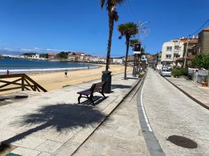 a bench on a sidewalk next to a beach at Panxón Primera Linea Mar in Nigrán