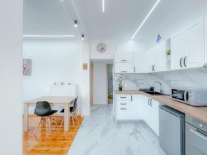 a kitchen with white cabinets and a wooden table at AYA Luxury Home - free public parking in Thessaloniki