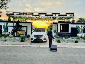un uomo che trascina una valigia davanti a un'auto di 24 On Basil Boutique Luxury Hotel a Johannesburg