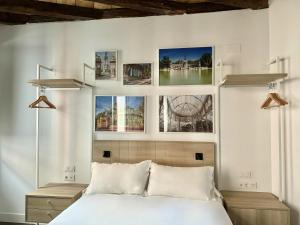 1 dormitorio con cama blanca y cuadros en la pared en CavaBajaSuites, en Madrid