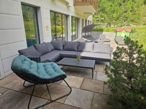a patio with a couch and a table and a grill at Chasa Castello relax & spa in Samnaun