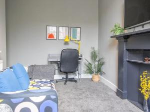 a living room with a couch and a chair and a fireplace at Pass the Keys West End Cosy Pop of Colour in Glasgow