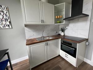 a small kitchen with white cabinets and a sink at Pass the Keys West End Cosy Pop of Colour in Glasgow