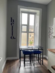 a dining room table with blue chairs in front of a window at Pass the Keys West End Cosy Pop of Colour in Glasgow