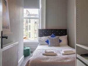 a small bedroom with a bed with a window at Pass the Keys West End Cosy Pop of Colour in Glasgow