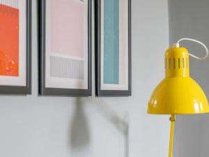 a yellow lamp in front of a wall with pictures at Pass the Keys West End Cosy Pop of Colour in Glasgow