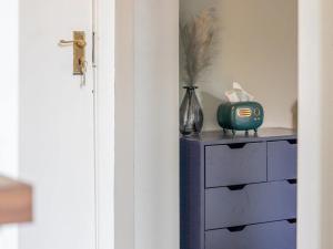 a blue dresser with a vase and a clock on it at Pass the Keys West End Cosy Pop of Colour in Glasgow