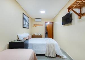 a bedroom with a bed and a tv on the wall at Hotel Santa Maria in Pirenópolis