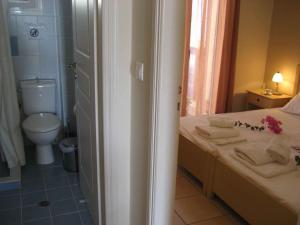 a bathroom with a toilet and a sink and a bed at Fyri Ammos Residences in Agia Pelagia