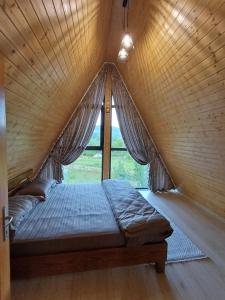 a bed in a wooden room with a window at COLȚ DE RAI - A Frame in Corbi