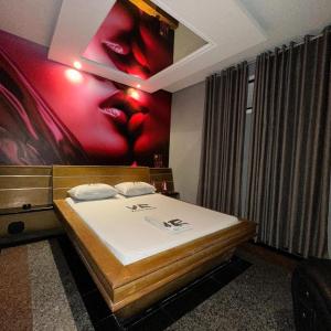 a bedroom with a bed with a painting on the wall at Motel Vitória Reggia in São Vicente