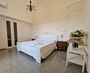 a white bedroom with a bed and a table at Residenza "I Tre Carrubi " in Fasano