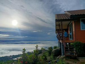 a person on a balcony of a house with a view at Nuea Tawan at Phu Thap Buek in Ban Tha Kok Hai