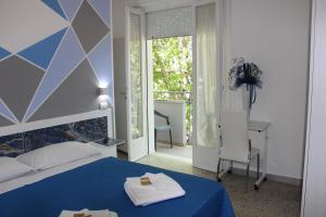 ein Schlafzimmer mit einem blauen Bett und einem Tisch und einem Schreibtisch in der Unterkunft Martina's Hotel in Rimini