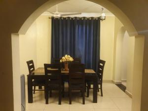 mesa de comedor y sillas con cortina azul en HOME TO STAY Apartments, en Mombasa 5 fotos más