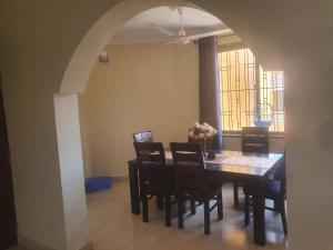 Un comedor con mesa y sillas y una ventana. en HOME TO STAY Apartments, en Mombasa