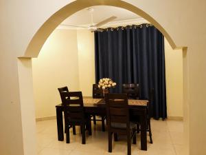mesa de comedor con sillas y cortina negra en HOME TO STAY Apartments, en Mombasa