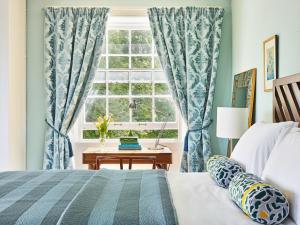 a bedroom with a bed and a window with blue curtains at Harrabeer Country House in Yelverton
