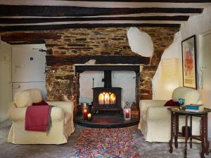 a living room with a stone fireplace with two chairs at Harrabeer Country House in Yelverton