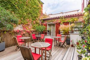 Un patio con mesas y sillas en una terraza de madera. en Hôtel La Marisa Grande Plage, en San Juan de Luz