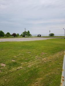 a field of grass with a road in the distance at Appartement de la rive in Shippagan